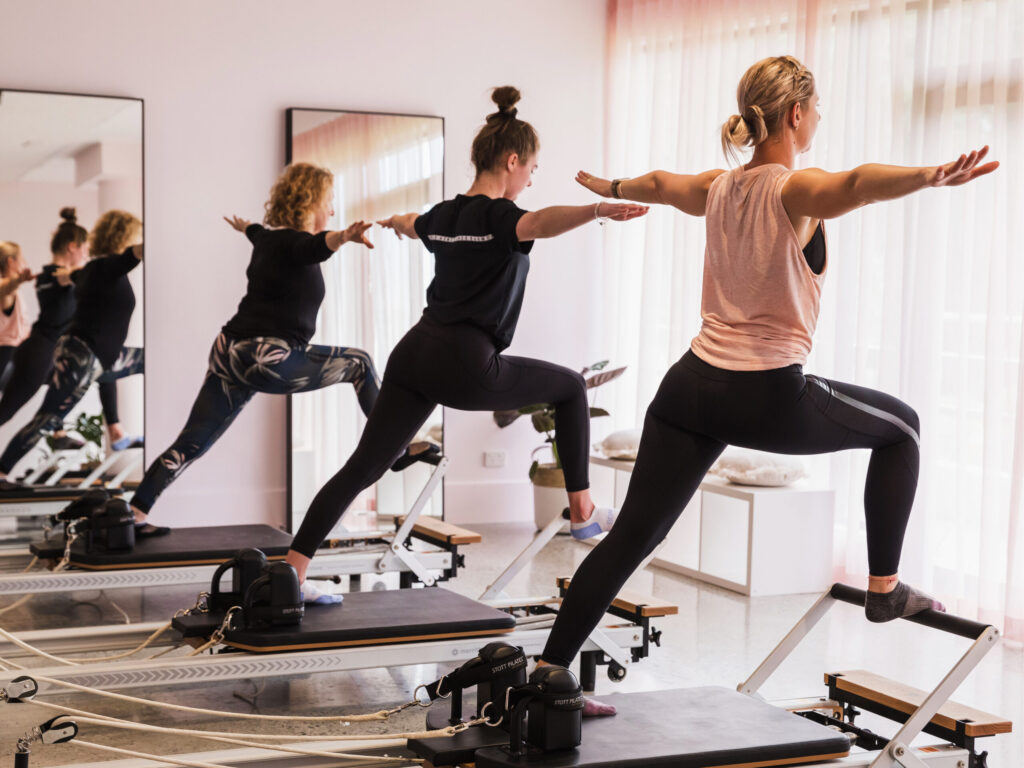 Three women using reformer pilates machine